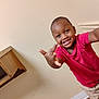 beige_wall, boy, casual_clothing, child, floor, hand_gesture, happy, home, indoor, light, person, playful, portrait, red_shirt, room, short_hair, sleeve, smiling, wood_floor, young