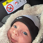 Maël participe au concours pour gagner de l'argent avec cette photo : airbag_warning, baby, beanie, blue_eyes, car_seat, child, closeup, cozy, cute, face, fluffy, indoor, infant, jacket, nike, person, portrait, smile, warm_clothing, zipper