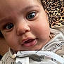 baby, close_up, face, blue_eyes, chubby_cheeks, infant, cute, animal_print, leopard_pattern, clothing, onesie, portrait, skin, person, indoors, child, young, expression, human, soft
