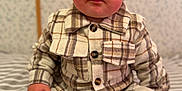 Alessyo participe au concours pour gagner de l'argent avec cette photo : baby, child, plaid_jacket, beige_clothing, white_sneakers, striped_bedspread, indoor, portrait, cute, sitting, curious_expression, soft_lighting, patterned_wallpaper, closeup, person, young_child, casual_wear, face, hands, footwear