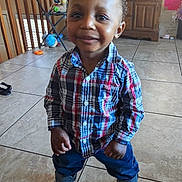 Rayvon is registered to the contest to win money with this photo: blue_pants, boy, chairs, child, colorful_clothing, furniture, happy, home, indoors, looking_at_camera, plaid_shirt, playroom, portrait, smiling, sneakers, standing, tiled_floor, toddler, toys, wooden_cabinet