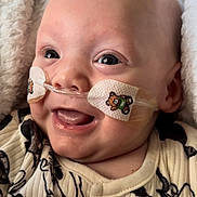 Bentley is registered to the contest to win money with this photo: baby, infant, smiling, face, nasal_tube, teddy_bear_stickers, blanket, onesie, clothing, closeup, healthcare, cute, happy, child, portrait, skin, head, expression, indoors, comfort