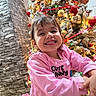 celebration, cheerful, child, christmas_tree, cute_bunny_text, decorations, face, festive, happy, holiday_lights, home, indoor, joy, long_sleeve, ornaments, person, pink_sweatshirt, seasonal, smiling, toddler