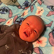 Delijah is registered to the contest to win money with this photo: animal_print, baby, baby_clothes, blanket, blue, cartoon, clothing, cute, expression, fabric, face, head, indoors, infant, lying_down, newborn, onesie, pattern, person, soft