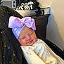 baby, infant, smiling, headband, bow, blanket, clothing, face, sleeping, person, indoors, furniture, table, fabric, black, purple, cozy, cute, resting, portrait