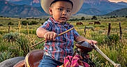 Jose Maria joined the competition — help win amazing prizes! boots, child, cowboy_hat, fence, field, grass, horse, jeans, mountains, nature, outdoor, plaid_shirt, riding, rope, rope_coil, saddle, sky, sunset, toddler, western