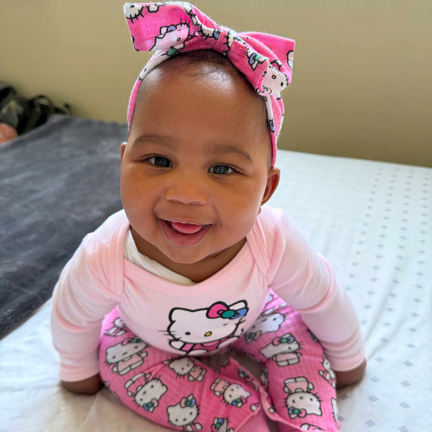 Nzuzo is registered to the contest to win money with this photo: apparel, baby, bed, blanket, child, cute, face, happy, headband, headwear, hello_kitty, indoor, infant, person, pink_clothing, portrait, sitting, smiling, sock, young_child