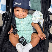 Akari is registered to the contest to win money with this photo: baby, child, smile, cap, stroller, onesie, sock, green_stripes, cute, infant, happy, seated, portrait, cloth, headwear, baby_blanket, hand, footwear, baby_toys, indoor