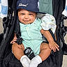 baby, child, smile, cap, stroller, onesie, sock, green_stripes, cute, infant, happy, seated, portrait, cloth, headwear, baby_blanket, hand, footwear, baby_toys, indoor