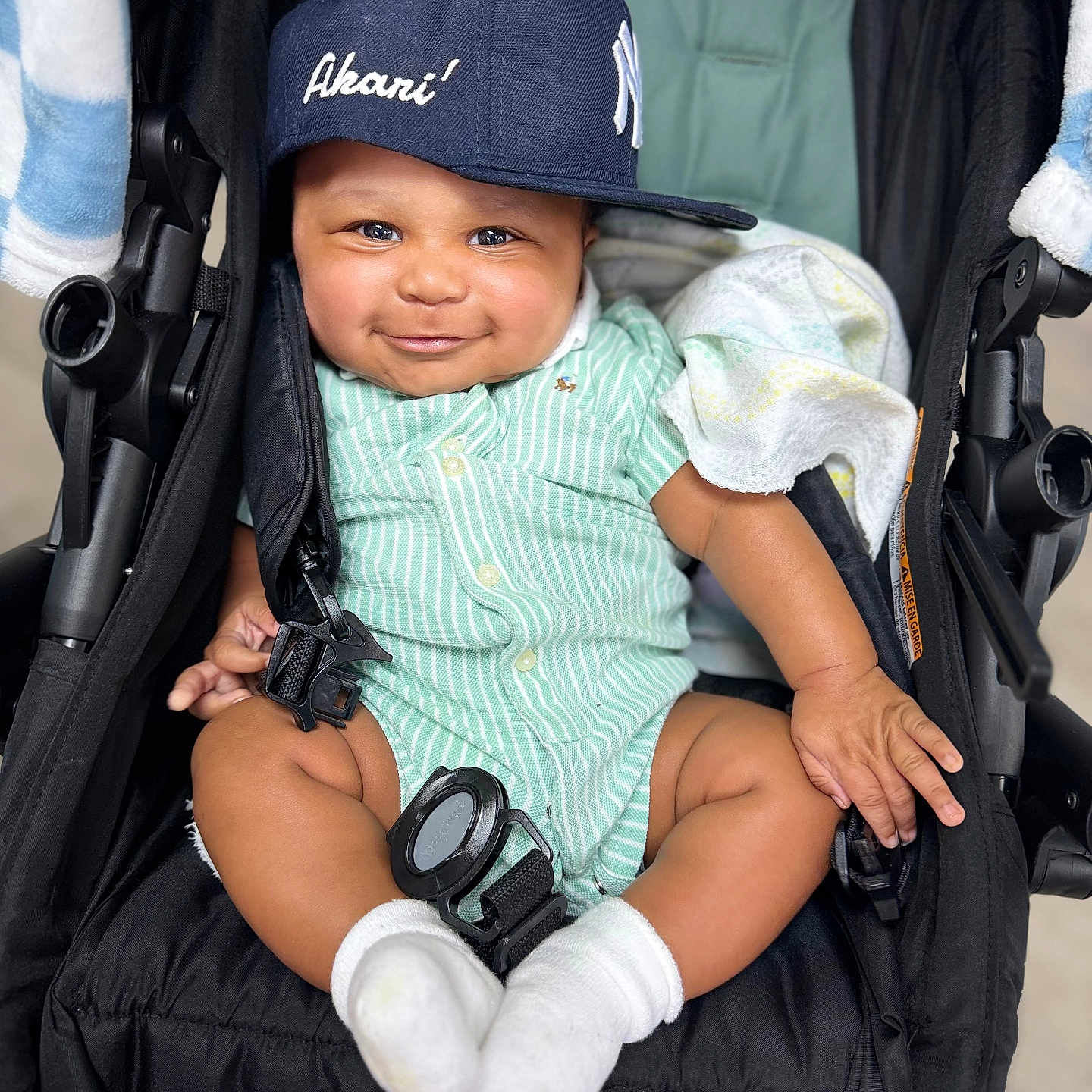 Akari is registered to the contest to win money with this photo: baby, child, smile, cap, stroller, onesie, sock, green_stripes, cute, infant, happy, seated, portrait, cloth, headwear, baby_blanket, hand, footwear, baby_toys, indoor