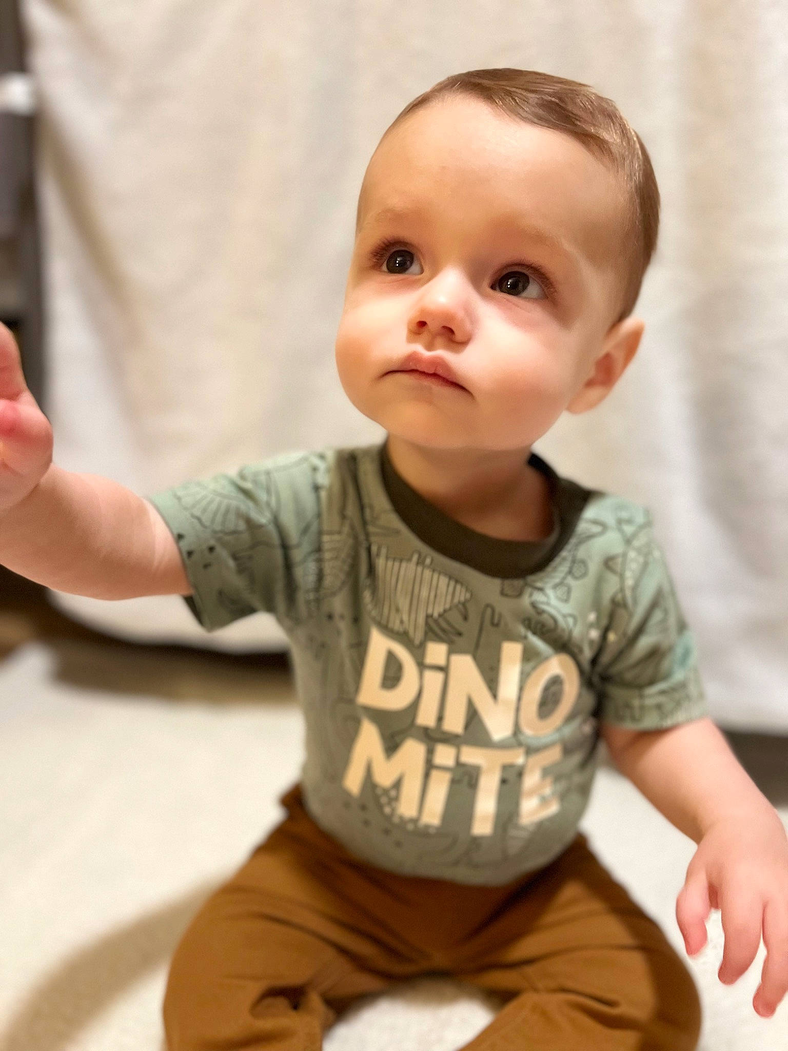 Alakai is registered to the contest to win money with this photo: baby, baby_toddler_clothing, cheek, elbow, face, finger, flooring, gesture, hand, happy, human_body, joint, neck, person, shoulder, skin, sleeve, standing, t_shirt, thumb