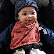 Sheridan joined the competition — help win amazing prizes! baby, infant, smile, hat, knit_hat, bib, car_seat, straps, clothing, cute, child, face, person, happy, indoors, baby_clothes, seat, safety, closeup, portrait