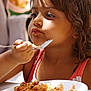 child, girl, fork, food, plate, meal, eating, table, indoor, closeup, focused, cute, summer_dress, brown_hair, sunlight, happy, person, child_eating, dining, casual