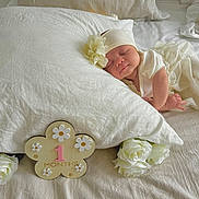 Laya participe au concours pour gagner de l'argent avec cette photo : baby, newborn, infant, sleeping, pillow, white_bed, blanket, flower, headband, one_month_marker, milestone_sign, roses, bedroom, soft_lighting, portrait, cute, peaceful, hands, dress, props