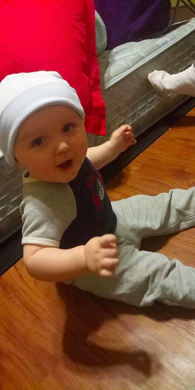 Braxton is registered to the contest to win money with this photo: arm, baby, beanie, bonnet, cap, child, christmas, fictional_character, finger, hand, headgear, headwear, leg, person, play, thumb, toddler, wood