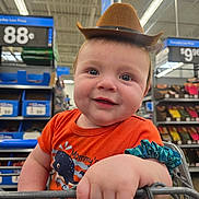 Damien is registered to the contest to win money with this photo: baby, blue_scrunchie, child, cowboy_hat, cute, hand, happy, indoor, infant, orange_shirt, person, portrait, price_tags, retail, shelves, shopping, shopping_cart, smiling, store_interior, whale_design
