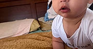 Lincoln Morales joined the competition — help win amazing prizes! baby, infant, child, face, portrait, bedroom, blanket, pillow, wooden_headboard, white_clothing, curious_expression, indoors, crawling, soft_texture, closeup, young_child, skin, person, head, eyes
