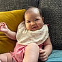 Romy participe au concours pour gagner de l'argent avec cette photo : baby, smiling, bib, pink_clothing, couch, cushion, yellow_cushion, teal_cushion, indoor, person, infant, happy, face, skin, hand, leg, relaxed, cute, child, portrait