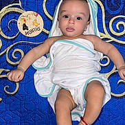 Liam is registered to the contest to win money with this photo: baby, infant, towel, blue_blanket, milestone_sign, 4_months, lying_down, curious_expression, wrapped, cute, child, portrait, soft_lighting, indoors, skin, hand, foot, red_bracelet, patterned_blanket, closeup
