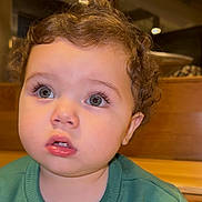 Jad joined the competition — help win amazing prizes! toddler, child, curly_hair, green_sweater, indoor, face, wide_eyes, expression, young_child, portrait, person, close_up, casual_clothing, seat, wooden_furniture, soft_lighting, innocence, cute, curiosity, young_face