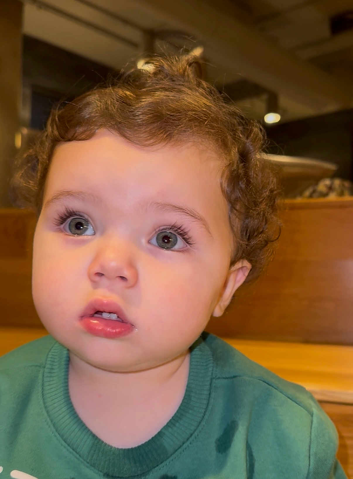 Jad joined the competition — help win amazing prizes! toddler, child, curly_hair, green_sweater, indoor, face, wide_eyes, expression, young_child, portrait, person, close_up, casual_clothing, seat, wooden_furniture, soft_lighting, innocence, cute, curiosity, young_face