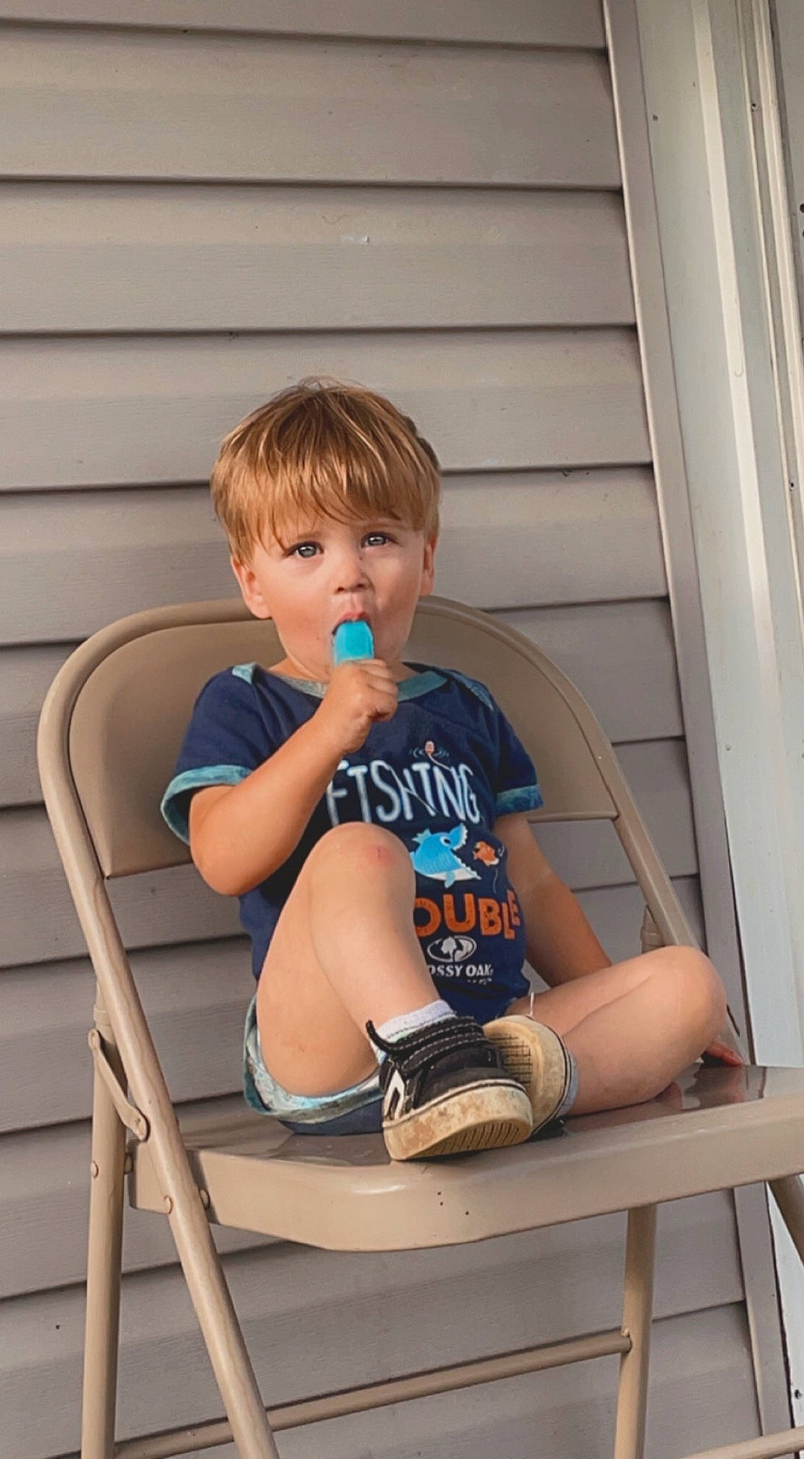 Karter is registered to the contest to win money with this photo: baby_toddler_clothing, blond, chair, child, comfort, electric_blue, foot, fun, hairstyle, human_leg, knee, leg, leisure, person, shorts, shoulder, sitting, t_shirt, thigh, toddler