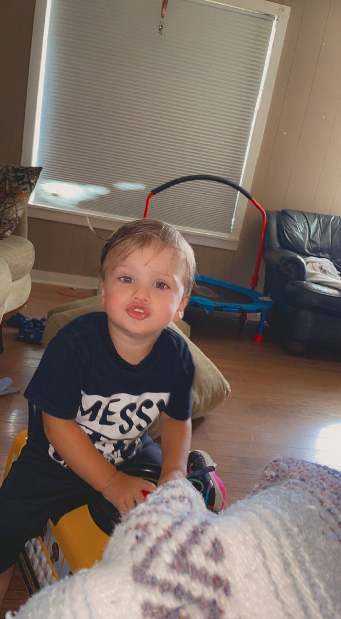 Karter is registered to the contest to win money with this photo: chair, child, comfort, floor, flooring, furniture, hardwood, human_leg, knee, lap, leg, living_room, mammal, person, shorts, sitting, smile, t_shirt, thigh, toddler