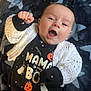 baby, infant, smiling, happy, clothing, black_outfit, ghost, pumpkin, halloween, blanket, stars, white_sweater, raised_fist, cute, portrait, indoors, face, person, lying_down, cozy