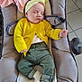 baby, sleeping, yellow_cardigan, green_pants, headband, baby_seat, blanket, pacifier, cushion, indoor, child, infant, resting, cozy, cute, soft, toddler, clothing, feet, peaceful