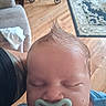 baby, infant, sleeping, pacifier, portrait, close_up, face, head, hair, spiky_hair, blue_clothing, indoors, home, wooden_floor, rug, chair, adult_arm, cozy, peaceful, photography