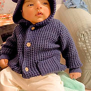 Shubh is registered to the contest to win money with this photo: baby, child, knitted_hoodie, navy_blue, hood_with_ears, white_pants, socks, blanket, indoor, couch, plush_toy, soft_toys, furniture, home, curious_expression, seated, cute, warm_clothing, infant, cozy