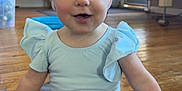 Aria joined the competition — help win amazing prizes! baby, blue_top, child, colorful, cute, floor, furniture, headwear, headwrap, home, indoor, living_room, mat, person, portrait, shorts, sitting, smiling, tie_dye, wooden_floor