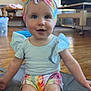 baby, blue_eyes, casual_clothes, child, colorful_clothing, curious_expression, cute, floor, headwear, headwrap, indoor, infant, living_room, mat, person, shorts, sitting, smiling, toddler, wooden_floor