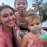 Delaney joined the competition — help win amazing prizes! child, toddler, adult, face_paint, blue_frosting, cupcake, outdoor, grass, smiling, playful, tongue_out, bunny_ears, family, summer, trees, casual_clothing, happy, celebration, fun, portrait