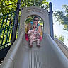 toddler, adult, slide, playground, sunglasses, smiling, outdoor, trees, sunlight, play_structure, child, fun, summer, happy, person, park, casual_clothing, daytime, recreation, family