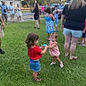 child, toddler, grass, outdoor, people, cupcake, food, dress, shorts, sandals, adult, gathering, social, summer, tree, car, road, casual, fun, friendship