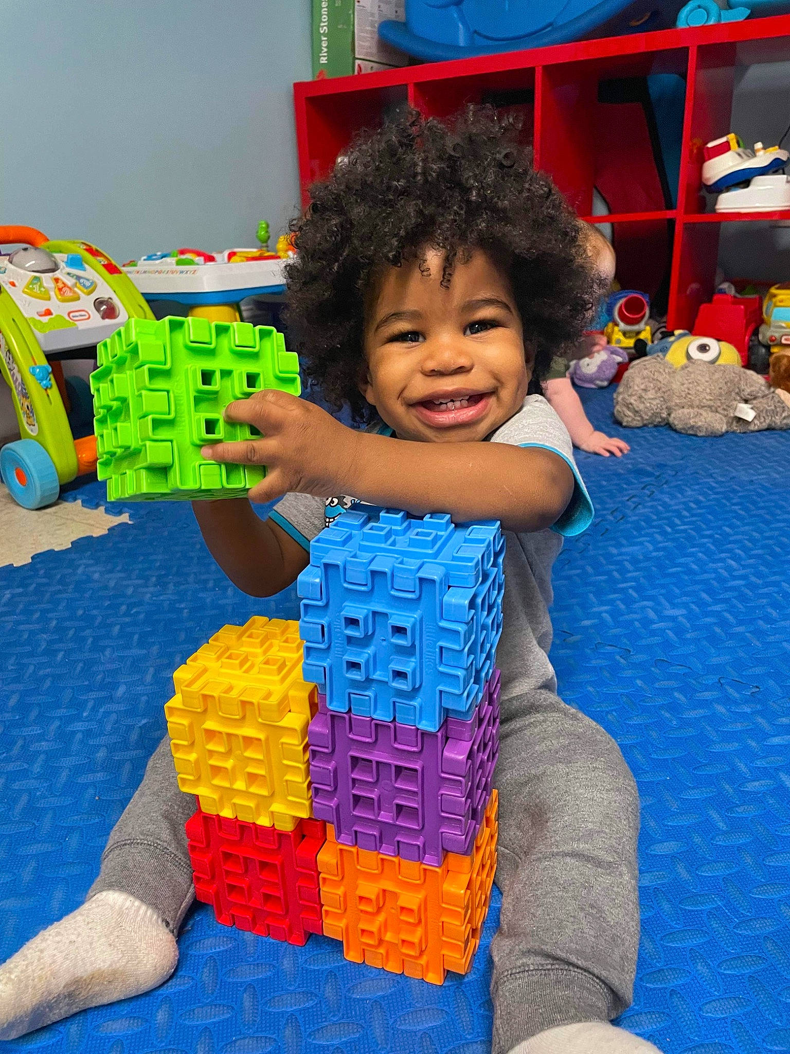 Legend is registered to the contest to win money with this photo: baby_toddler_clothing, child, electric_blue, fun, happy, joy, leisure, person, plastic, play, recreation, red, room, sitting, smile, t_shirt, thumb, toddler, toy, toy_block