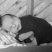 Maddux is registered to the contest to win money with this photo: newborn, baby, sleeping, wrapped, blanket, black_and_white, portrait, infant, peaceful, soft, texture, wooden_background, cushion, cozy, closeup, face, foot, hand, resting, peace