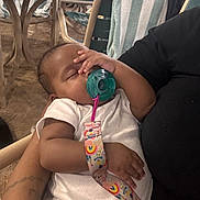 Lola is registered to the contest to win money with this photo: baby, sleeping, pacifier, arm, person, chair, towel, striped_towel, indoor, white_clothing, infant, holding, relaxing, closeup, resting, cute, peaceful, small_child, colorful_strap, furniture