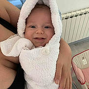 Liam a rejoint le concours — aidez-le/la à gagner de superbes lots ! baby, infant, towel, hooded_towel, smile, face, person, hand, skin, indoor, radiator, baby_rocker, furniture, comfort, warmth, cozy, closeup, portrait, newborn, cute