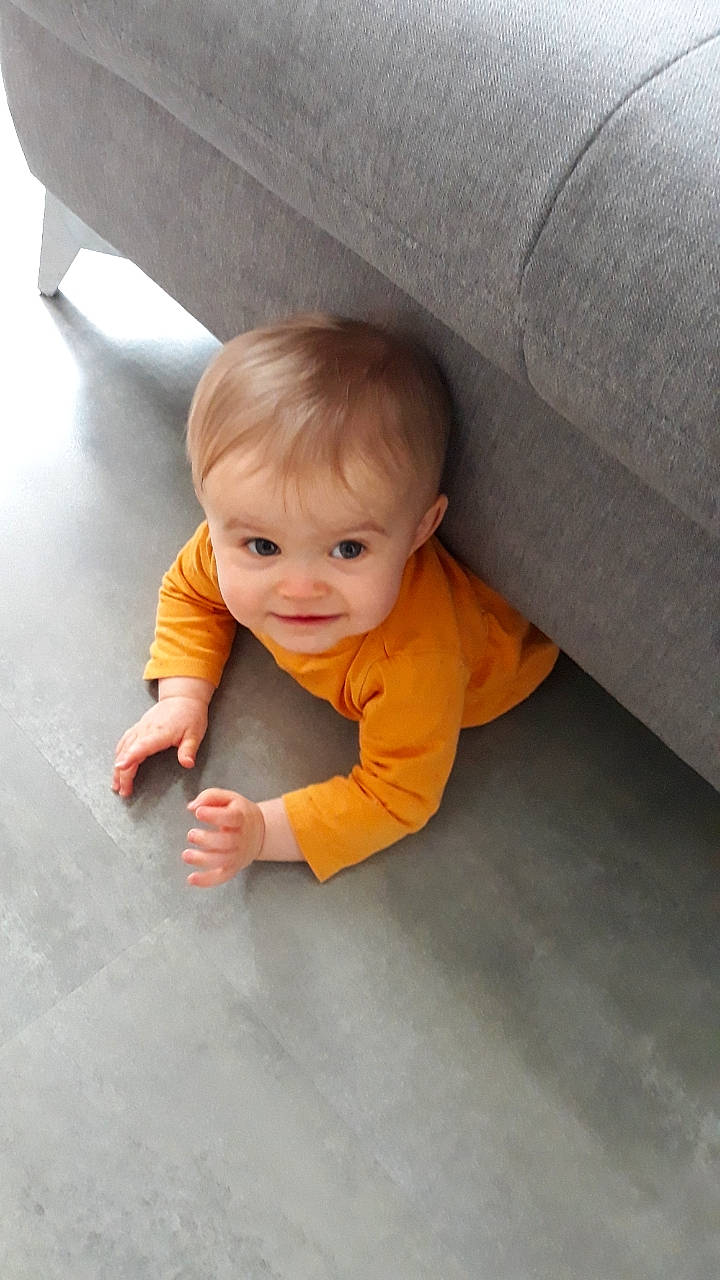 Camille participe au concours pour gagner de l'argent avec cette photo : asphalt, baby, baby_toddler_clothing, cheek, child, comfort, crawling, finger, floor, flooring, grey, hardwood, human_body, joy, nose, person, road_surface, sitting, skin, smile