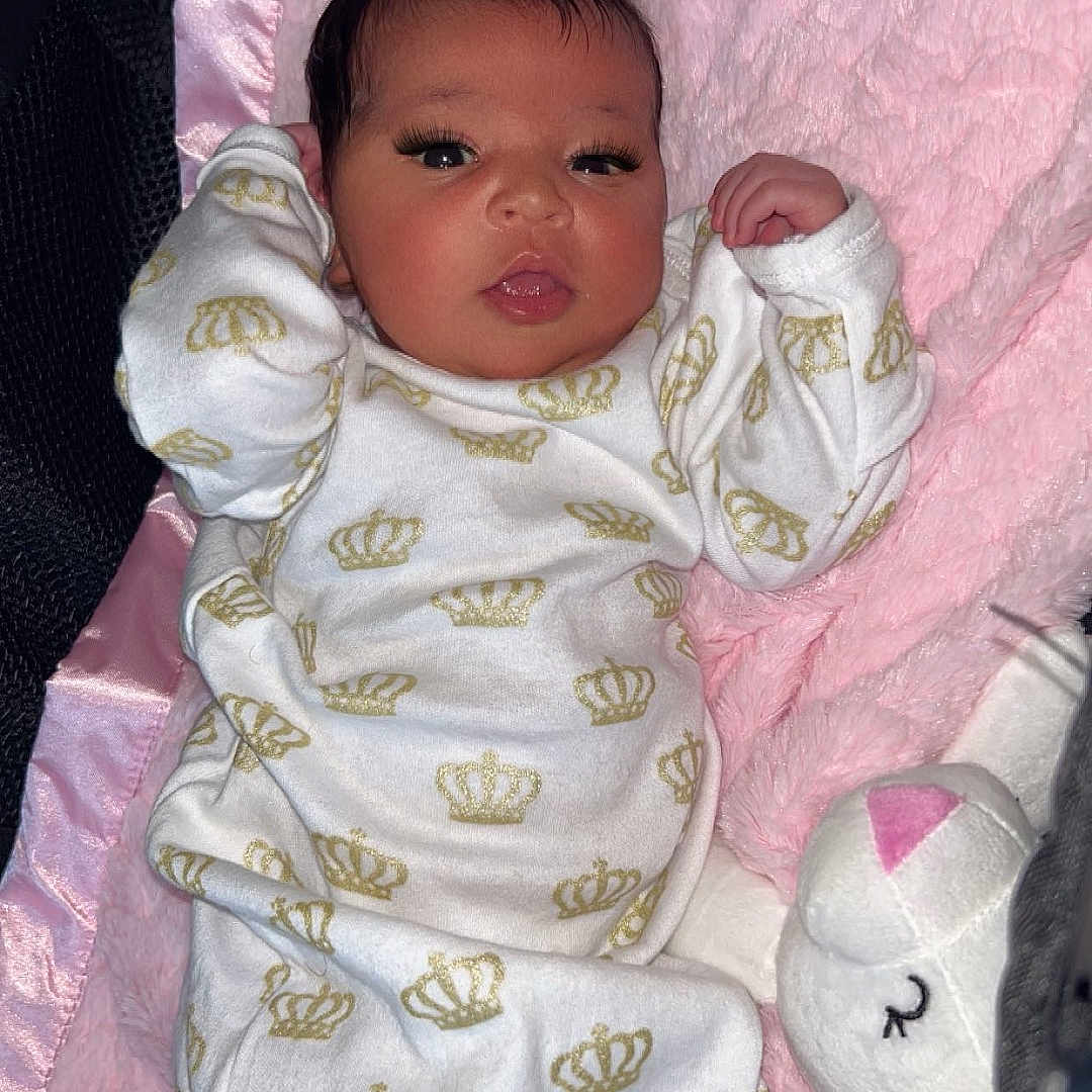 Lydia joined the competition — help win amazing prizes! adorable, baby, blanket, child, clothing, crown_pattern, cute, face, indoors, infant, lying_down, newborn, pink, plush, portrait, sleepwear, soft, stuffed_animal, white, young