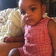 Tori is registered to the contest to win money with this photo: blanket, casual, child, closeup, cute, face, furniture, hand, home, indoor, natural_light, person, portrait, red_checkered_clothing, room, serious_expression, sitting, skin, toddler, young_child