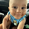 adorable, baby, blue_clothing, car, car_seat, child, close_up, eyes, face, happy, indoor, infant, looking_at_camera, pacifier, photography, portrait, sitting, smiling, toy, vehicle