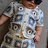 baby, child, sunglasses, crochet, clothing, bear_pattern, shorts, shirt, couch, furniture, indoor, portrait, cute, fashion, knitwear, relaxing, person, hand, face, eyewear