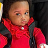 Rayanne is registered to the contest to win money with this photo: baby, child, infant, car_seat, red_clothing, ruffles, bow, face, eyes, skin, hair, curly_hair, seatbelt, closeup, portrait, expression, sitting, indoor, person, cute