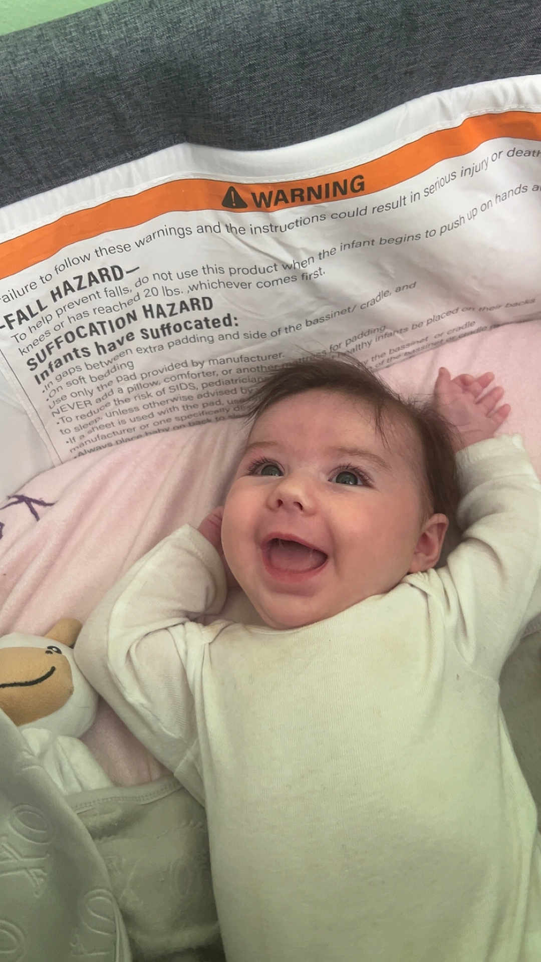 Shelby is registered to the contest to win money with this photo: baby, smiling, infant, crib, blanket, stuffed_toy, happy, face, child, soft_toys, clothing, lying_down, cute, indoors, head, person, young_child, baby_girl, white_clothing, cozy