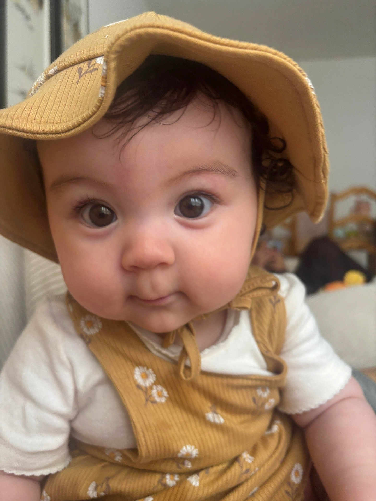 Pearl Yangchen Lhamo participe au concours pour gagner de l'argent avec cette photo : baby, child, face, hat, clothing, curly_hair, indoors, portrait, cute, expression, young_child, chubby_cheeks, looking_at_camera, yellow, floral_pattern, headwear, close_up, infant, person, white_shirt