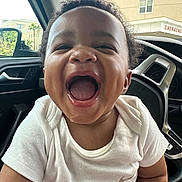 Zachary joined the competition — help win amazing prizes! toddler, child, smiling, laughing, car_interior, white_shirt, curly_hair, happy, portrait, face, mouth_open, seat, window, steering_wheel, daylight, building, emergency_sign, joy, cute, person