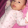 baby, infant, pink_onesie, blanket, soft_texture, cartoon_characters, cute, lying_down, indoor, child, face, expression, small_hands, sleepwear, portrait, young_child, comfortable, adorable, baby_clothes, resting